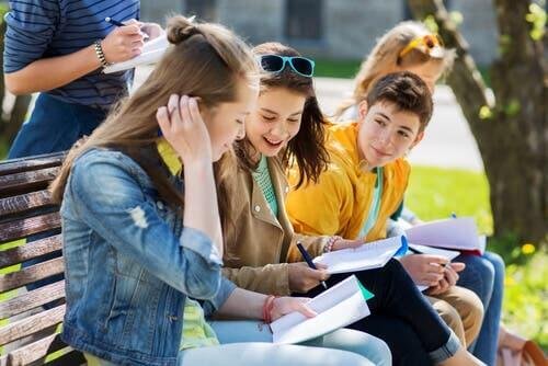 Quatre adolescents sur un banc, discutant ensemble pendant une activité d'été.