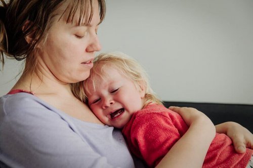 Un enfant qui pleure dans les bras de sa mère.